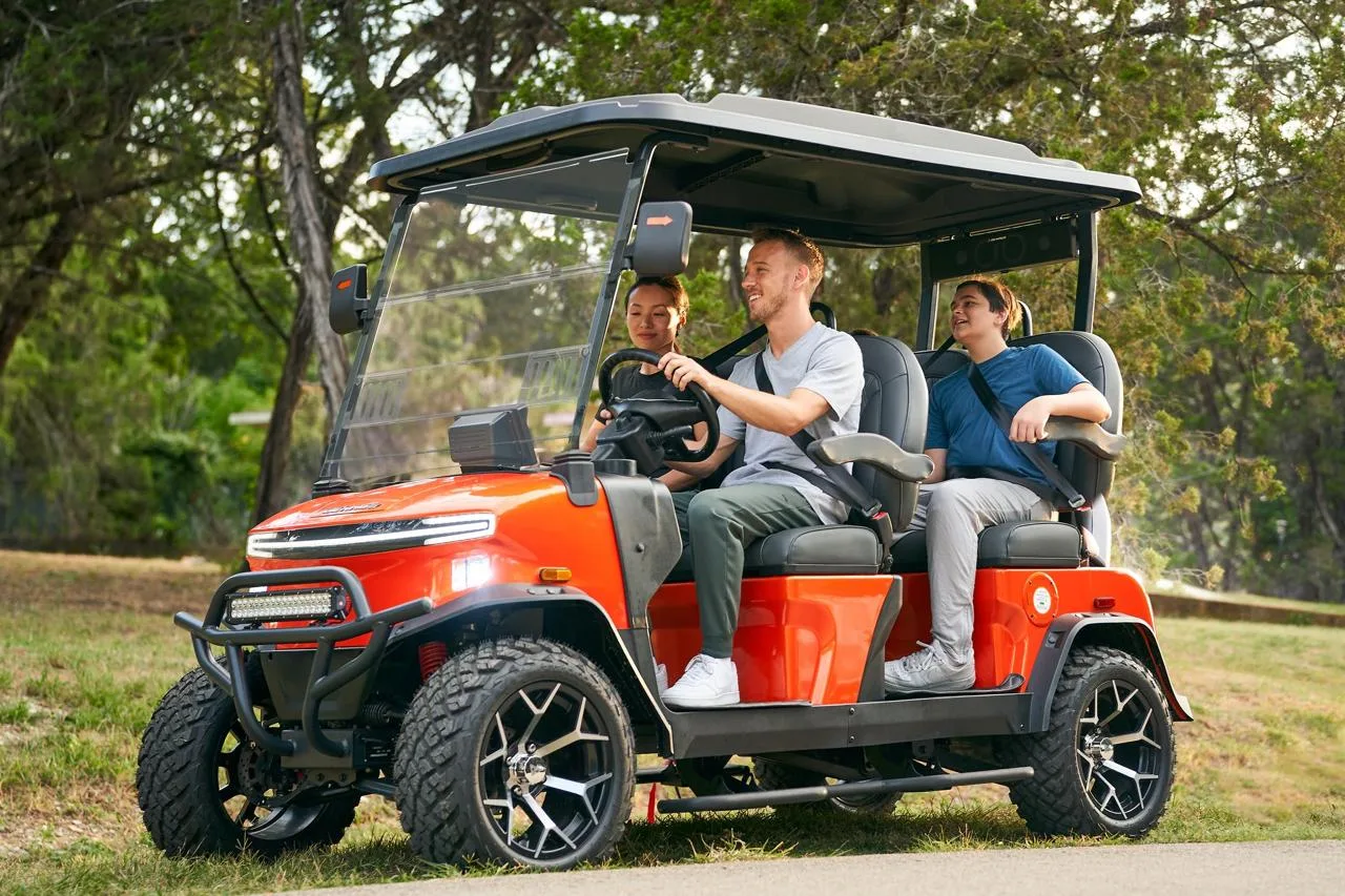 Carro de golf eléctrico Denago rojo con familia en campo de golf